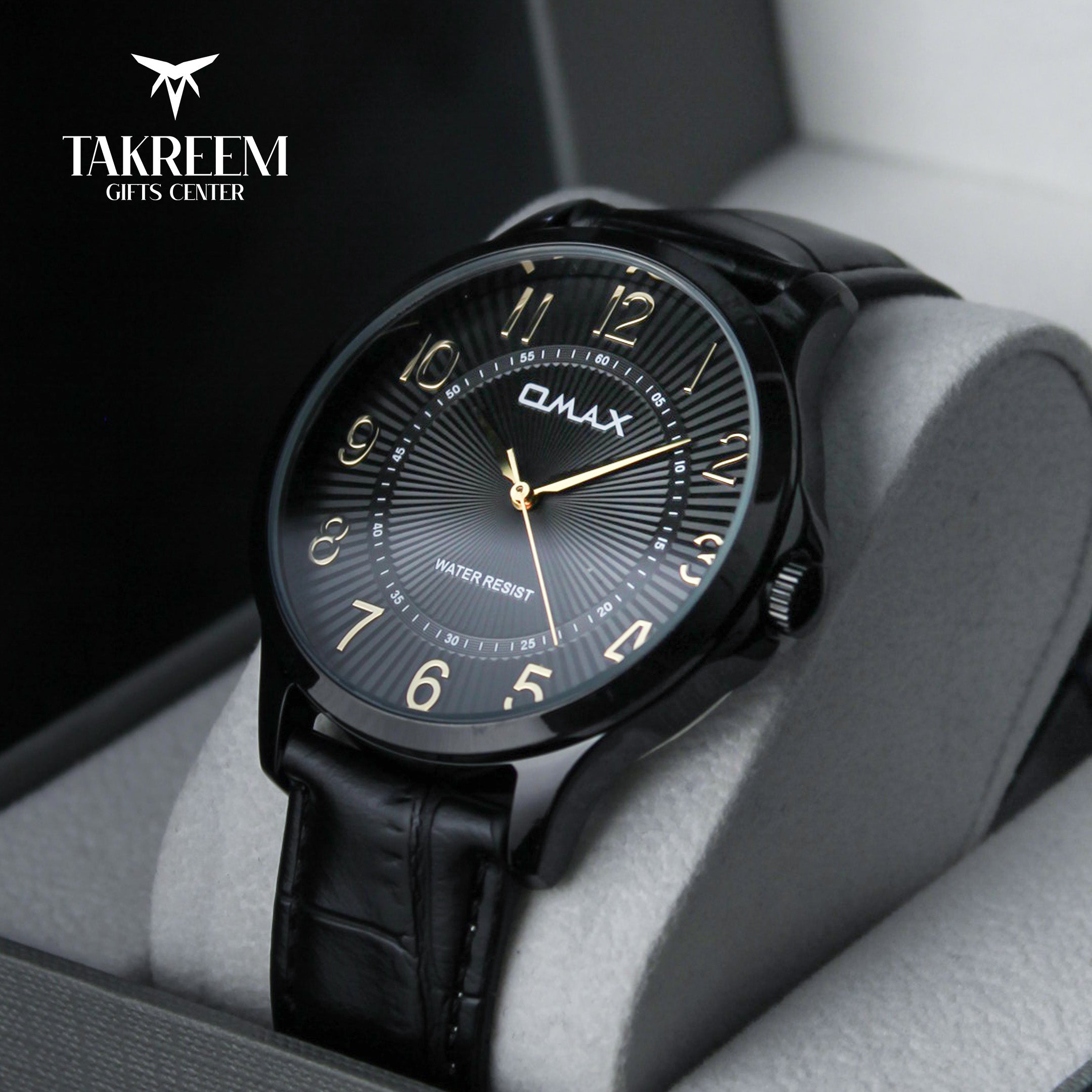 Black wristwatch with gold accents on a gray cushion, branded 'Takreem Gifts Center'.
