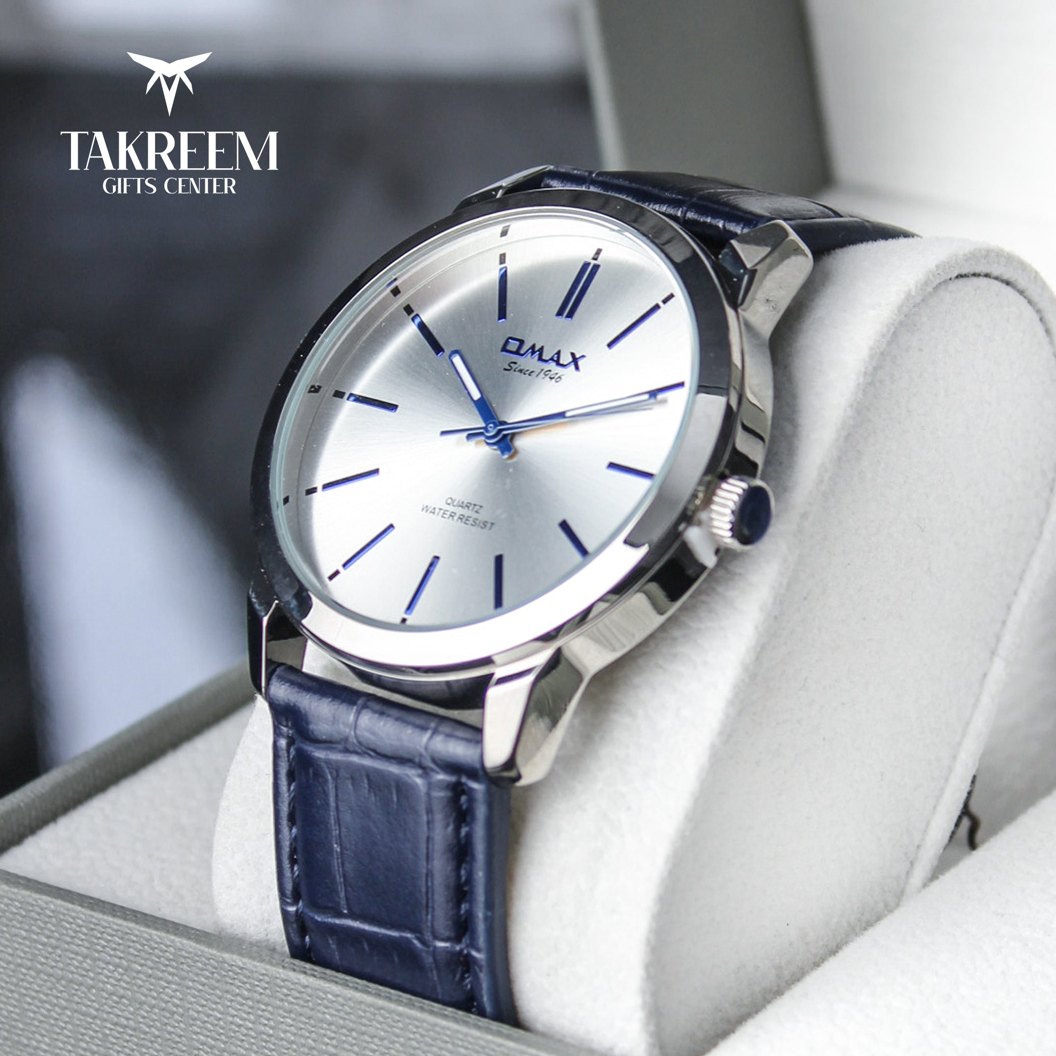 Wristwatch with blue leather strap on a white cushion, brand 'Takreem' visible