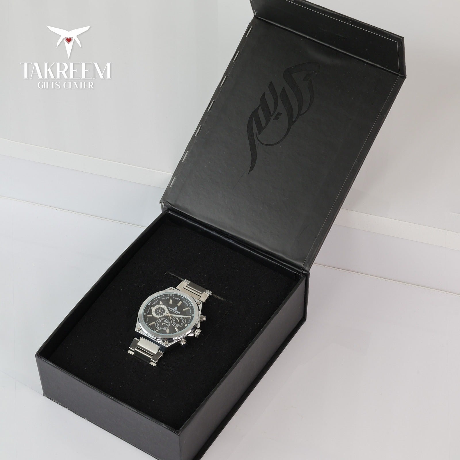 Silver watch in a black box with 'Takreem Gifts Center' branding.