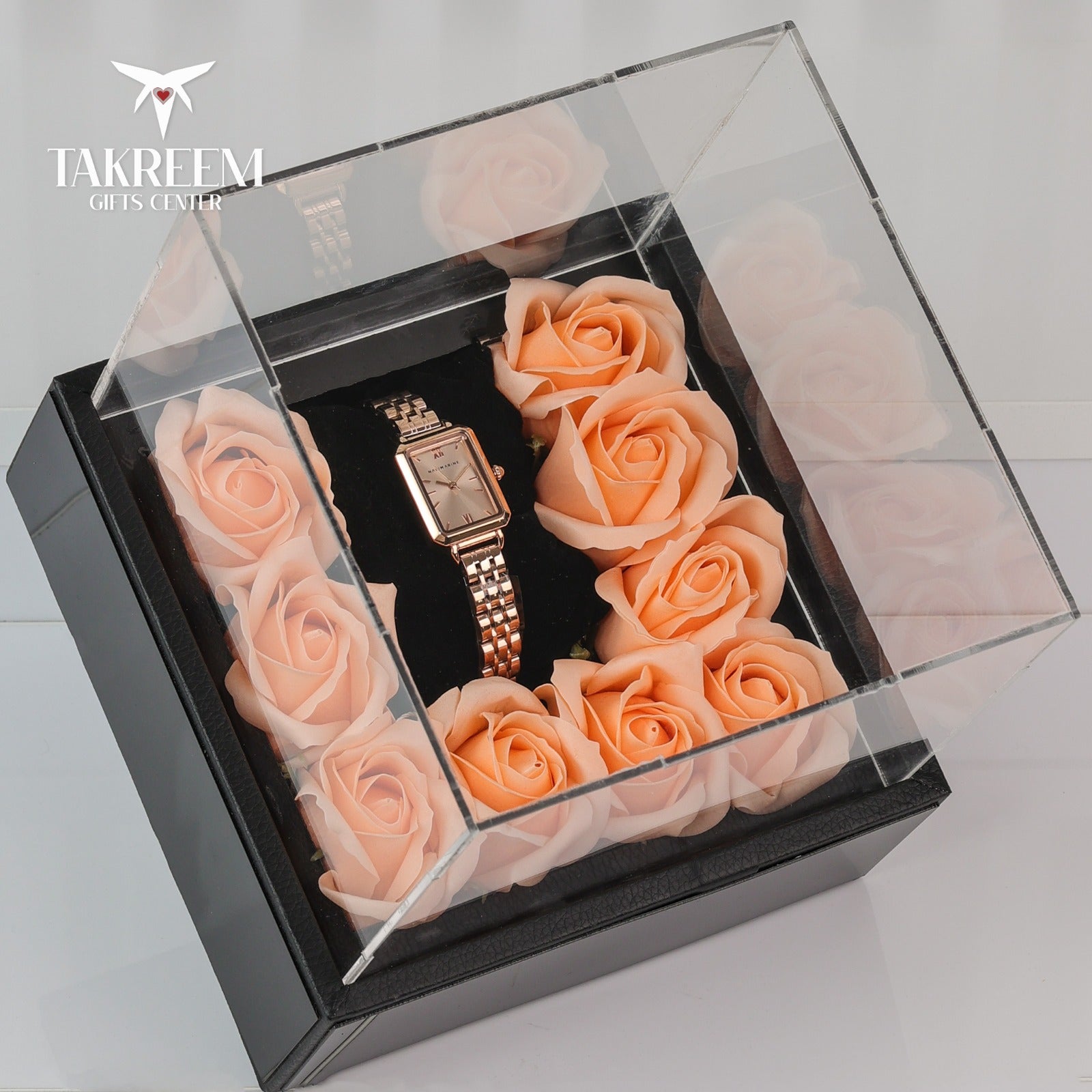 Watch encased in a transparent box with pink roses, brand 'Takreem' visible.