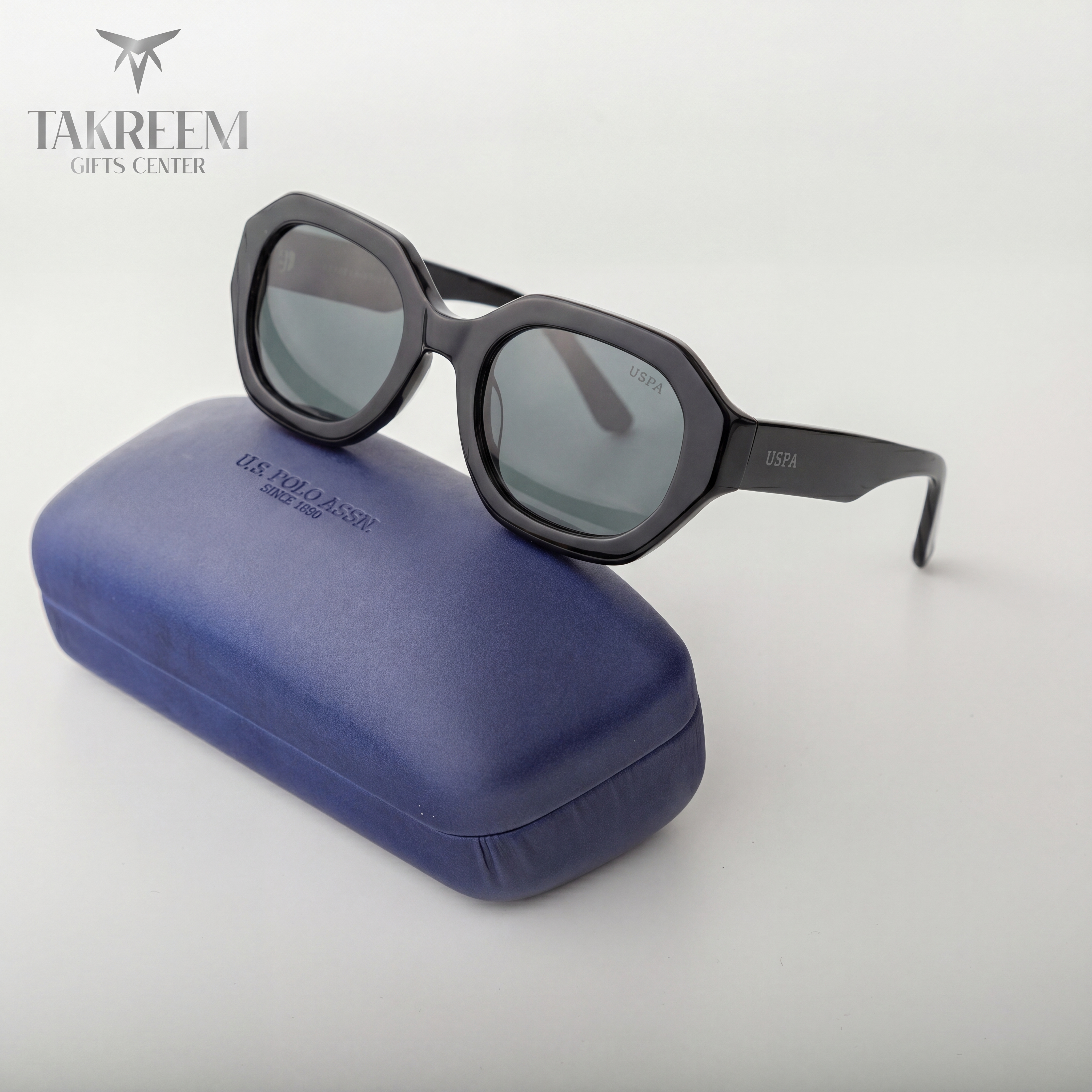 Black sunglasses on a blue case with 'Takreem Gifts Center' branding.