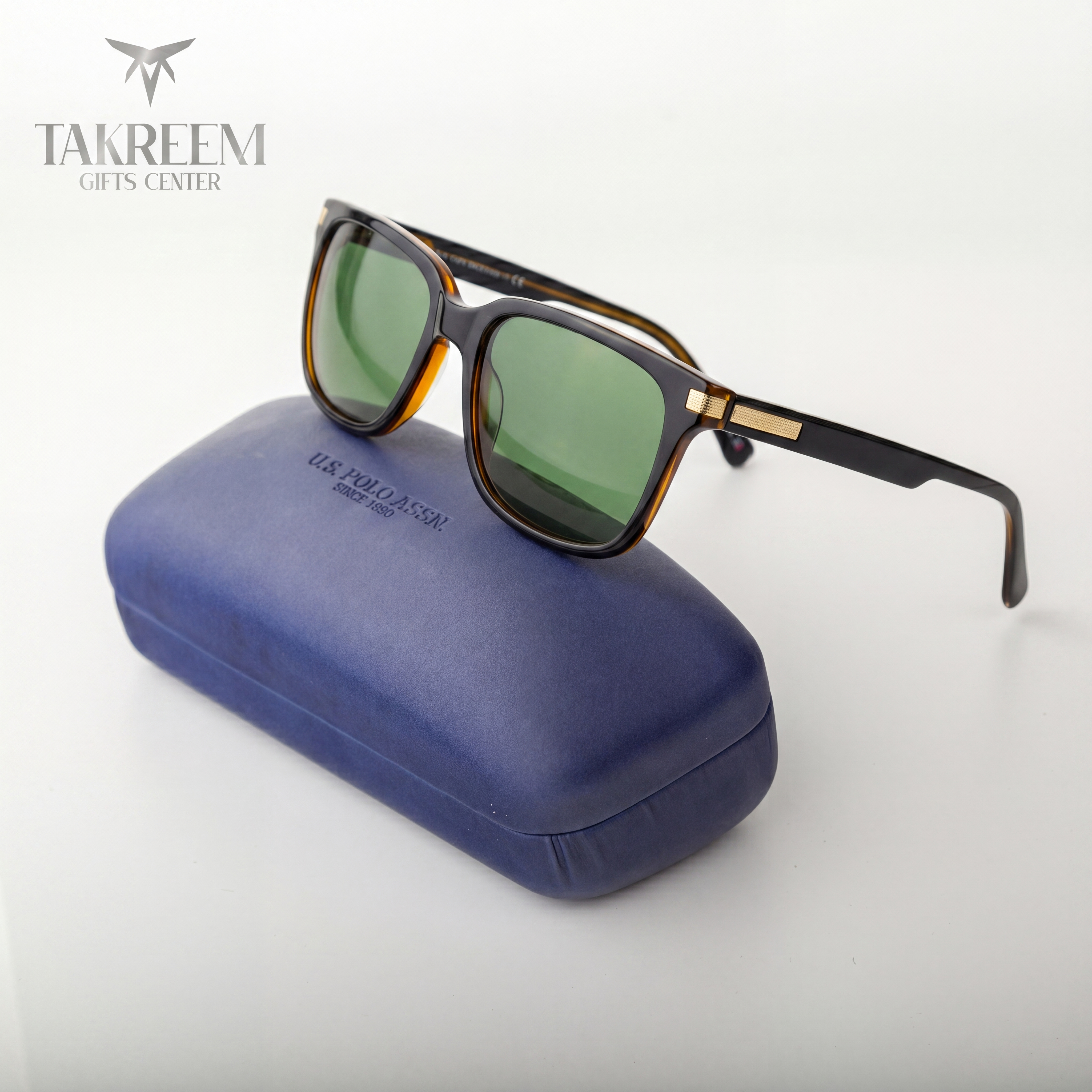 Sunglasses with green lenses on a blue case, branded 'Takreem Gifts Center'.