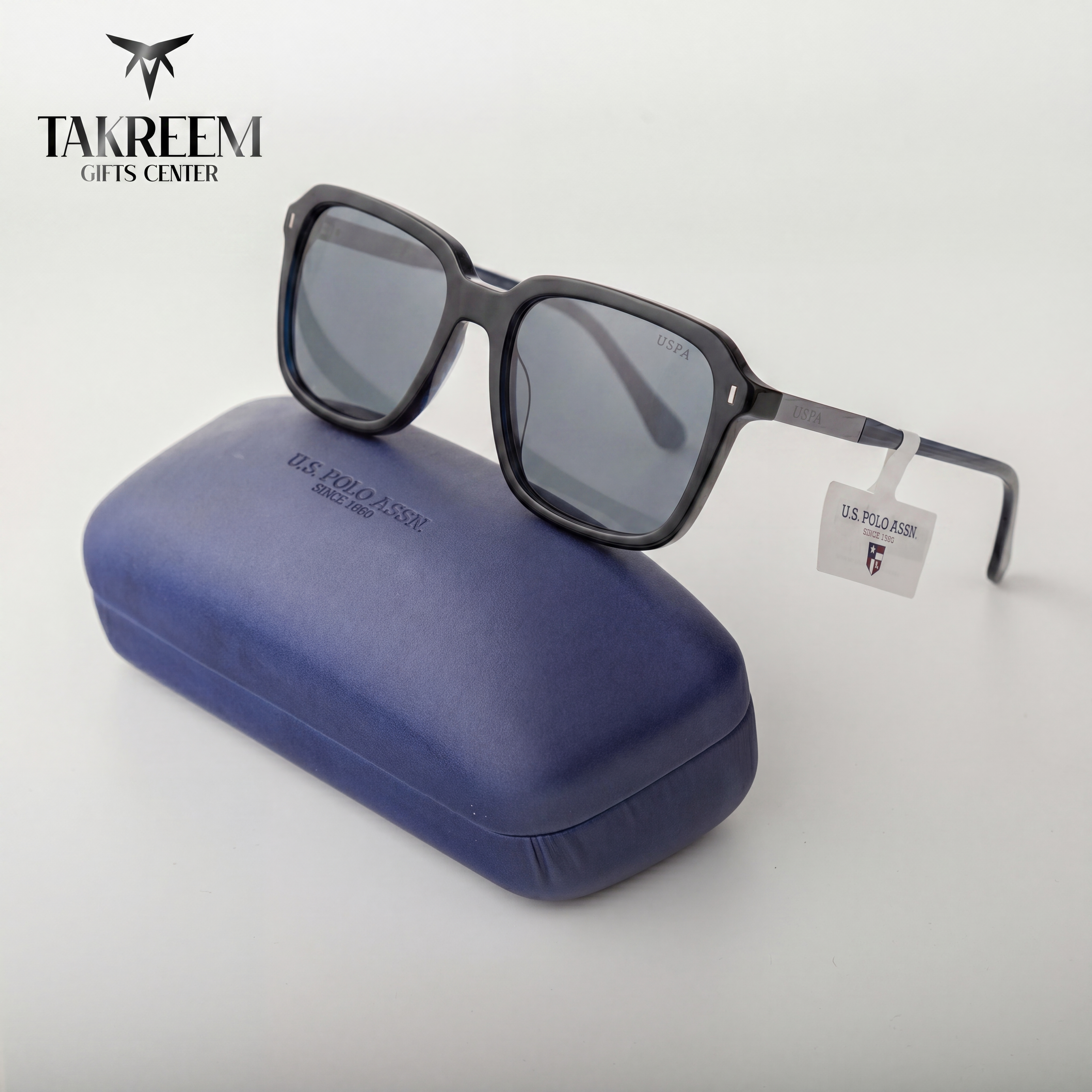 Black sunglasses with a blue case on a white background, featuring the US Polo Assn. logo.