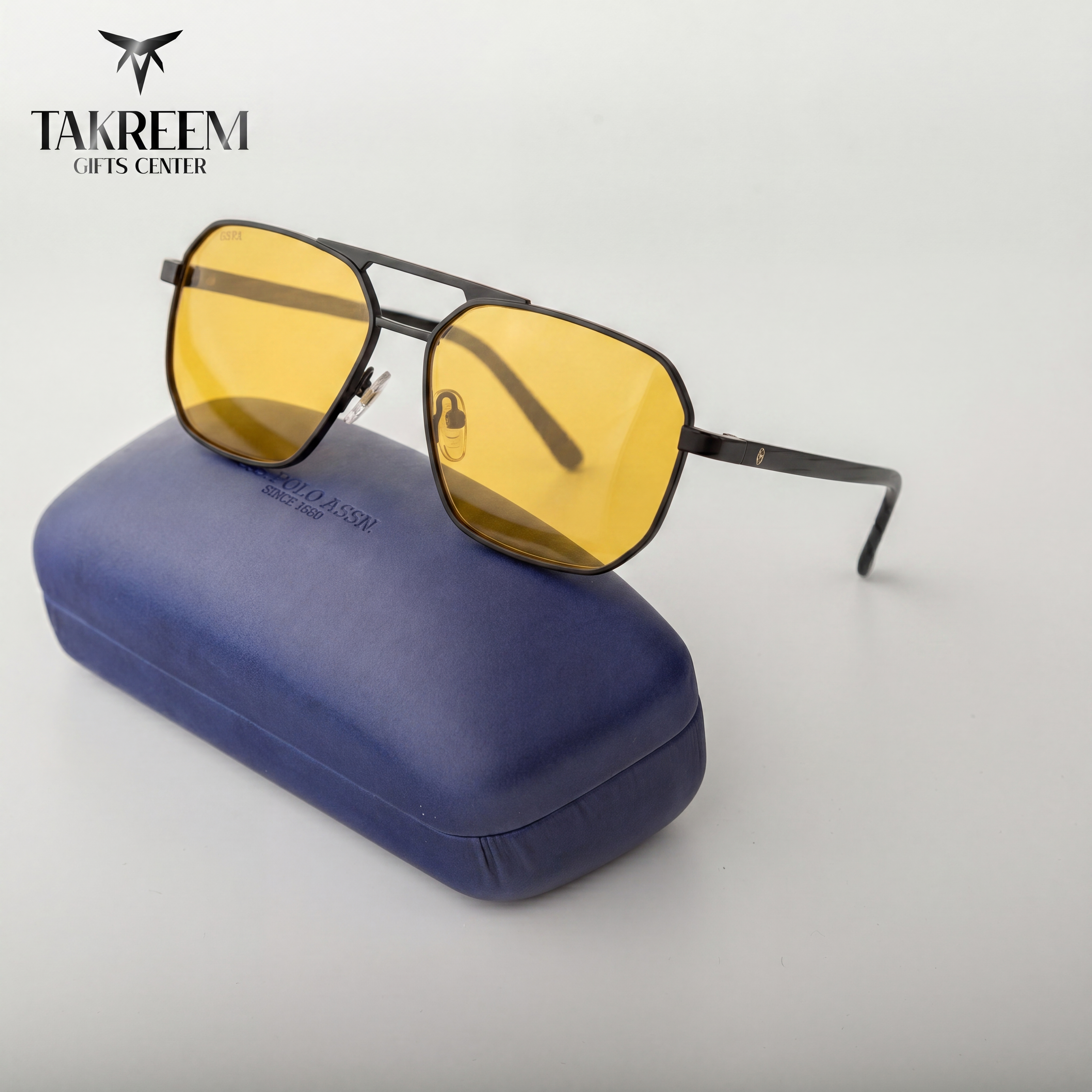 Sunglasses with yellow lenses on a blue case, brand 'Takreem' visible